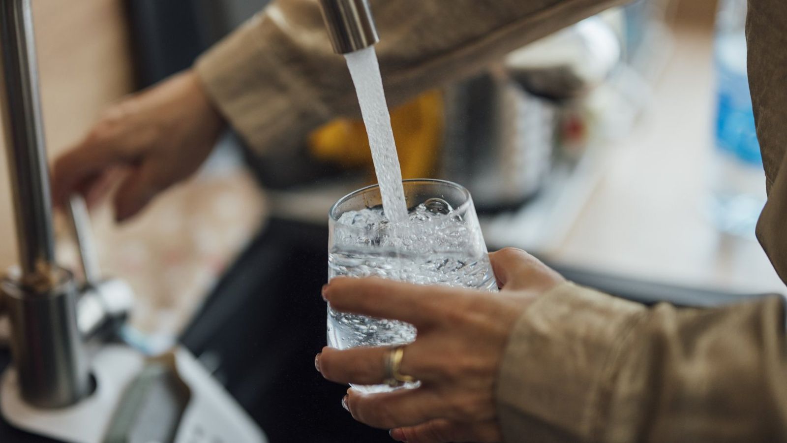 Glass being filled with water from a kitchen faucet
